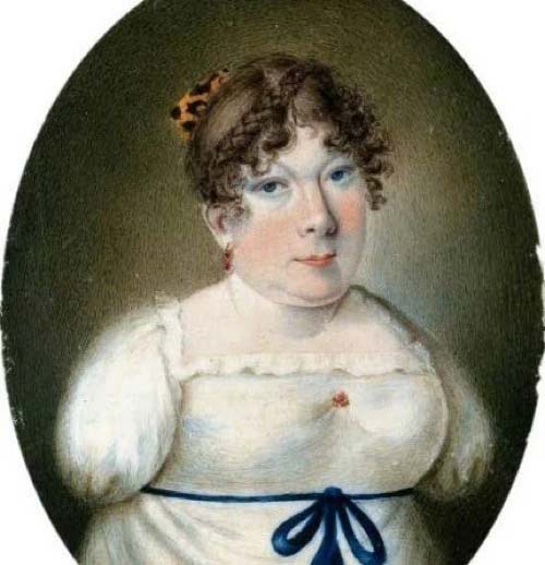 An oval miniature portrait depicting a woman with brown curly hair decorated with a tortoiseshell comb. She wears a white Empire-style dress with a blue ribbon tied in a bow at the waist and a small red accent on the bodice, gazing calmly forward with a neutral expression against a dark, textured background.